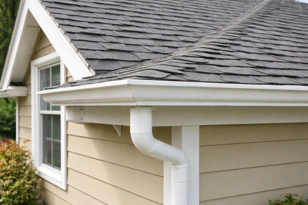 Roofing contractor Bellevue WA inspecting asphalt shingle roof and gutter system on a residential home.